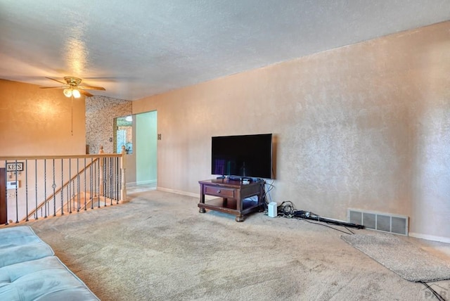 carpeted living room featuring a textured ceiling, a ceiling fan, visible vents, and baseboards