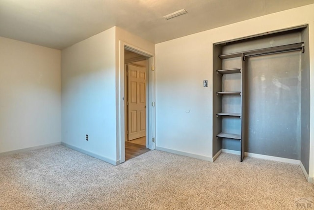 unfurnished bedroom featuring baseboards, a closet, and light colored carpet