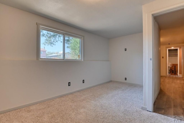 empty room featuring baseboards and light colored carpet