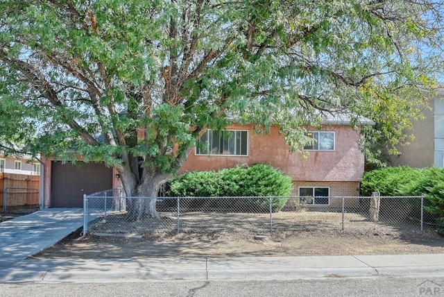 view of front of property featuring driveway, brick siding, fence, and stucco siding