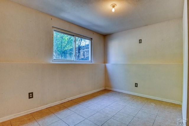 spare room with light tile patterned flooring and baseboards