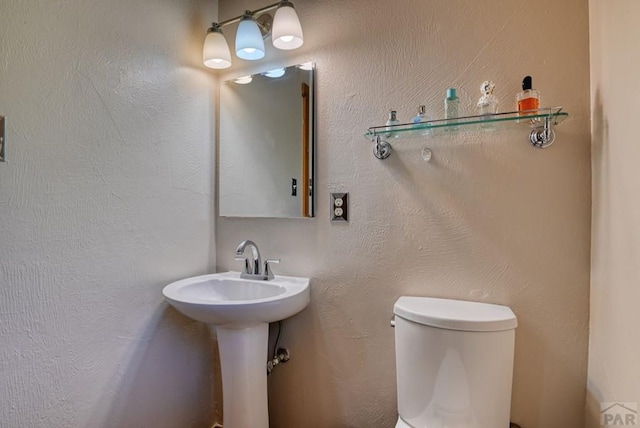 half bathroom featuring a textured wall and toilet