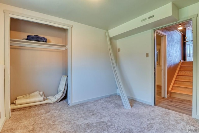 unfurnished bedroom featuring baseboards, a closet, visible vents, and light colored carpet