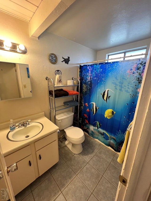 bathroom featuring a textured wall, toilet, tile patterned floors, vanity, and a shower with curtain