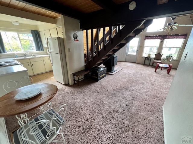 living room with light carpet, stairway, beamed ceiling, and plenty of natural light