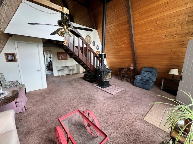 unfurnished living room featuring ceiling fan, a wood stove, vaulted ceiling, carpet floors, and wood walls