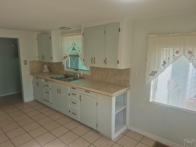 1122 Raton Ave, La Junta, CO 81050 - kitchen with backsplash, light tile patterned floors, tile counters, and white cabinets
