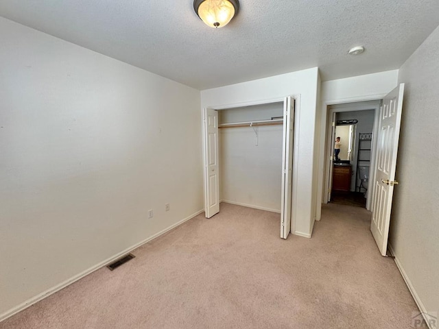 4147 Outlook Blvd Unit F, Pueblo, CO 81008 - unfurnished bedroom with baseboards, a closet, light carpet, a textured ceiling, and visible vents