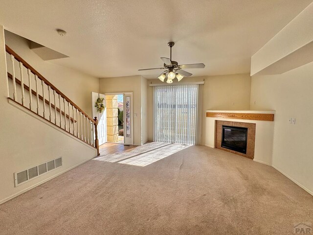 4147 Outlook Blvd Unit F, Pueblo, CO 81008 - unfurnished living room with visible vents, stairway, carpet flooring, and a fireplace