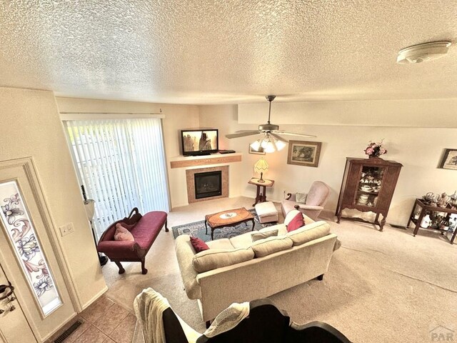 4147 Outlook Blvd Unit F, Pueblo, CO 81008 - living area with visible vents, a ceiling fan, carpet, a textured ceiling, and a tile fireplace