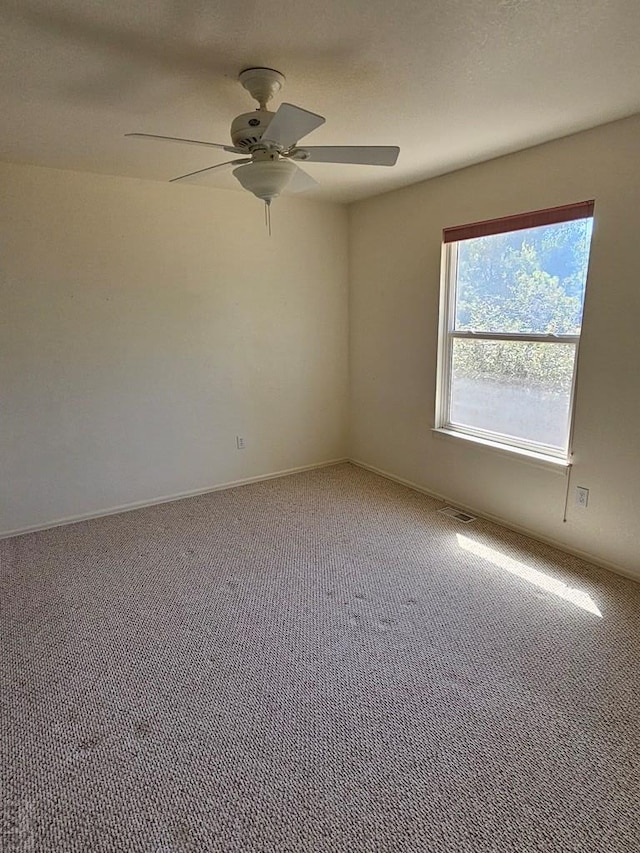 spare room with carpet, a ceiling fan, and baseboards