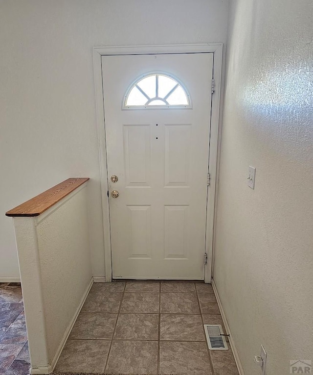 doorway with visible vents, baseboards, and tile patterned floors