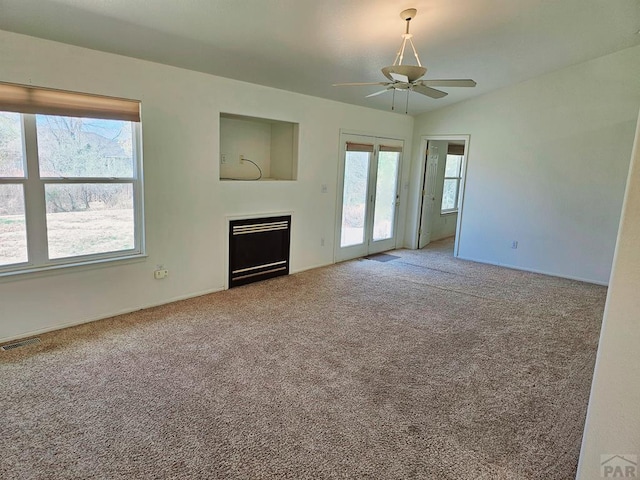 unfurnished living room featuring a fireplace, carpet flooring, visible vents, and a ceiling fan