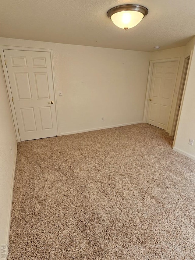 carpeted empty room with a textured ceiling and baseboards