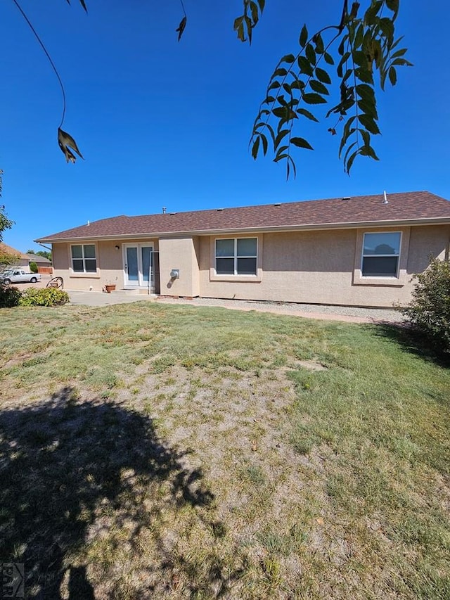 back of property with a lawn and stucco siding