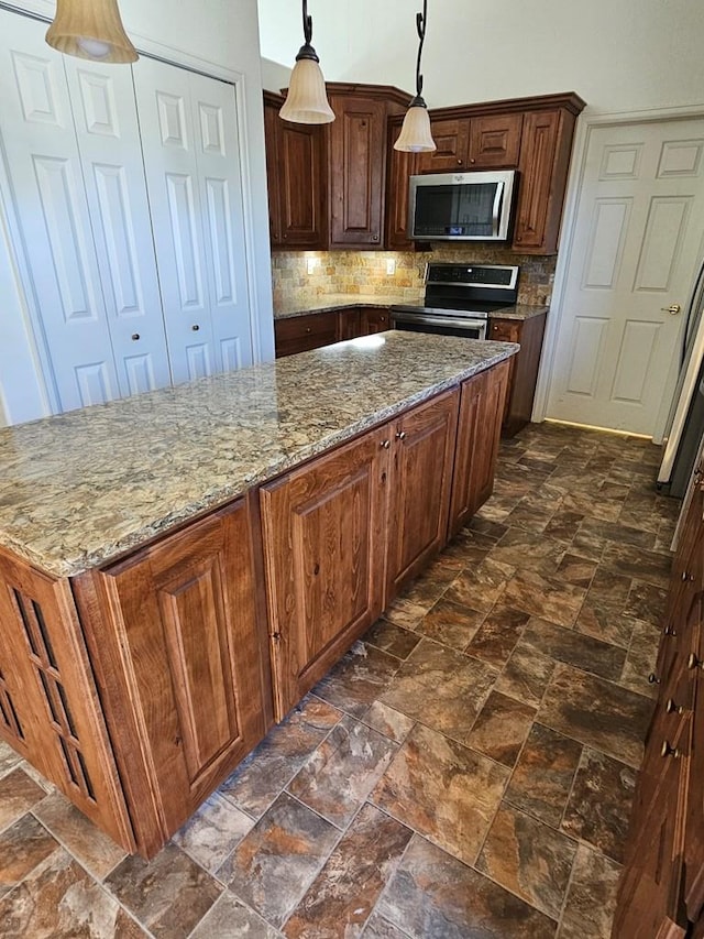 kitchen featuring tasteful backsplash, light stone counters, stainless steel appliances, and decorative light fixtures