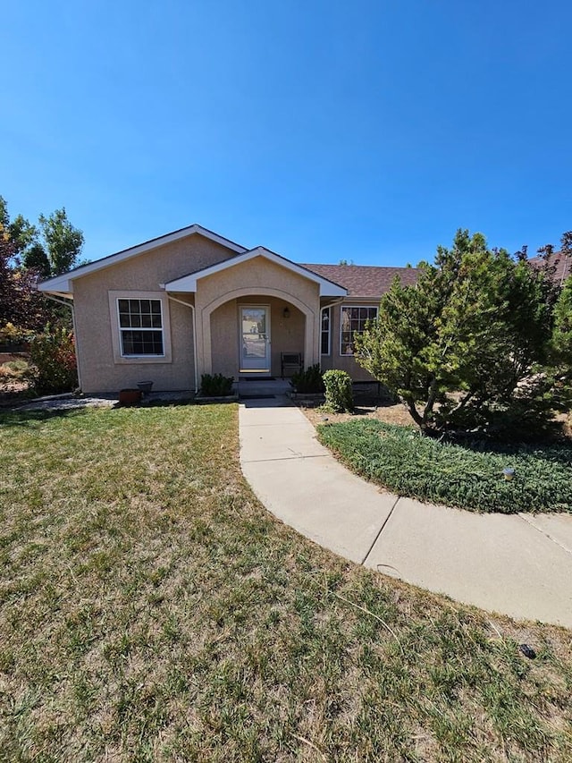 single story home featuring stucco siding and a front yard