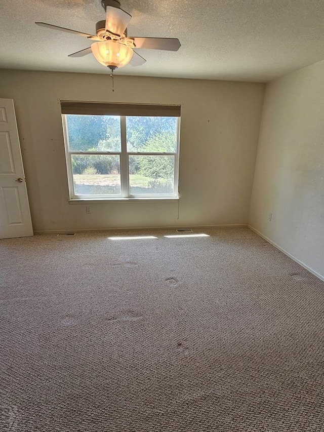 carpeted spare room with a ceiling fan, a textured ceiling, and baseboards