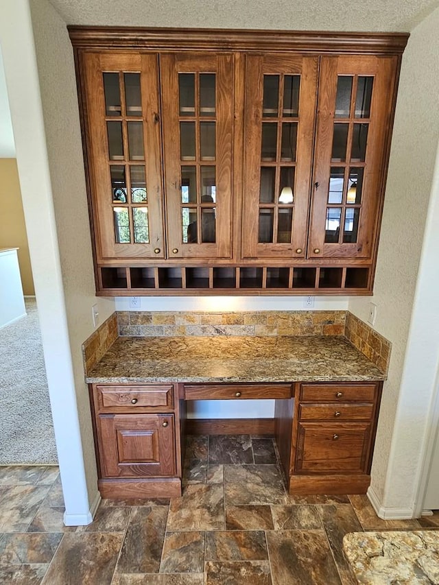 bar featuring stone finish flooring, baseboards, and built in desk