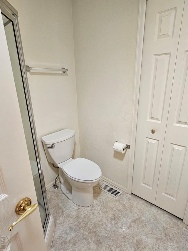 bathroom featuring toilet, visible vents, baseboards, a closet, and a shower stall