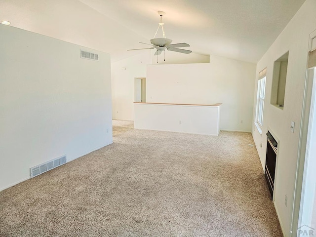 empty room with lofted ceiling, visible vents, a ceiling fan, and light colored carpet