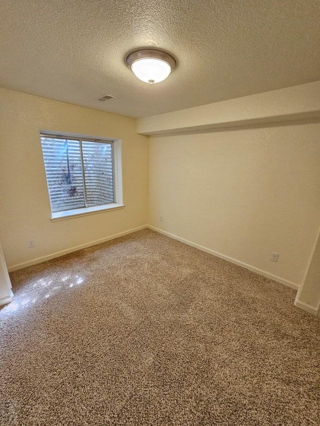 carpeted spare room with visible vents, a textured ceiling, and baseboards