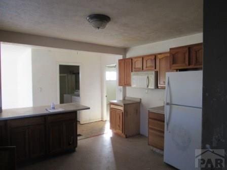 kitchen featuring light countertops, white appliances, and brown cabinetry