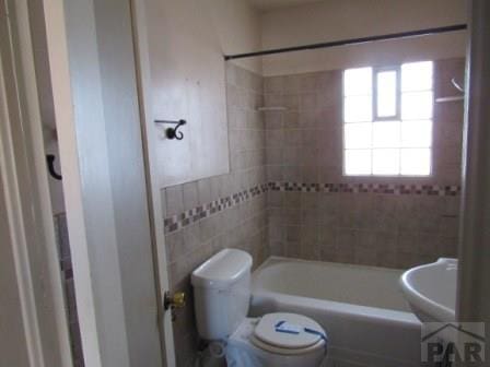 full bathroom with toilet, shower / tub combination, tile walls, and a sink