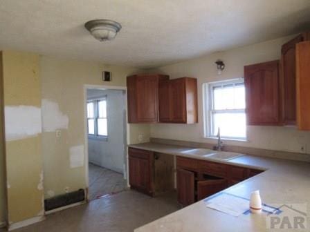 kitchen with brown cabinets, a wealth of natural light, light countertops, and a sink