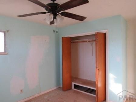 unfurnished bedroom with ceiling fan and a closet