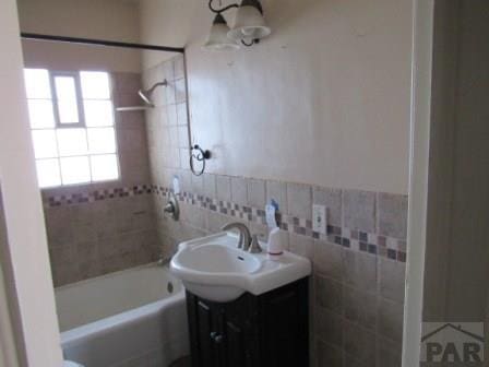 bathroom with  shower combination, tile walls, and vanity