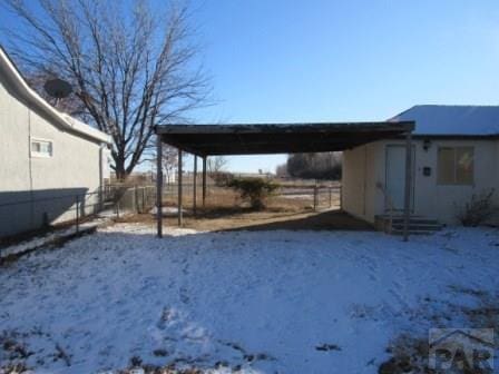 yard layered in snow featuring a carport and fence