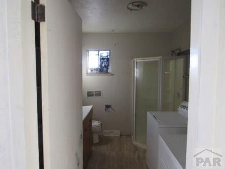 bathroom with washer / dryer, a stall shower, visible vents, toilet, and vanity