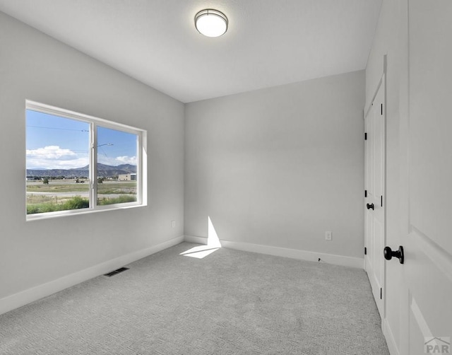 empty room with baseboards, visible vents, and light colored carpet