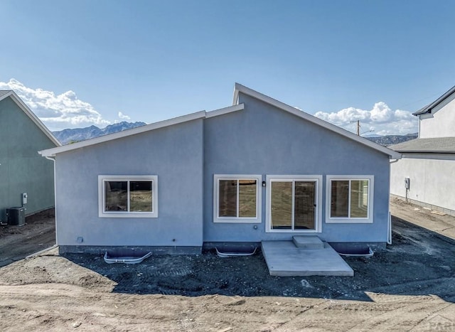 back of house with central AC, a patio, a mountain view, and stucco siding