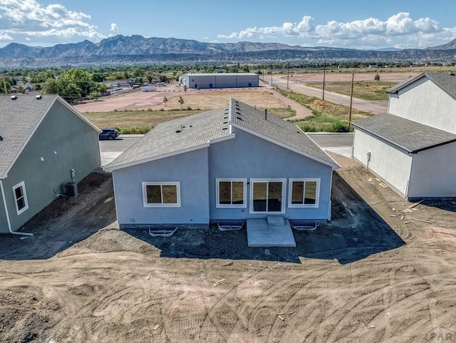 back of house with a patio area, a mountain view, central AC unit, and stucco siding