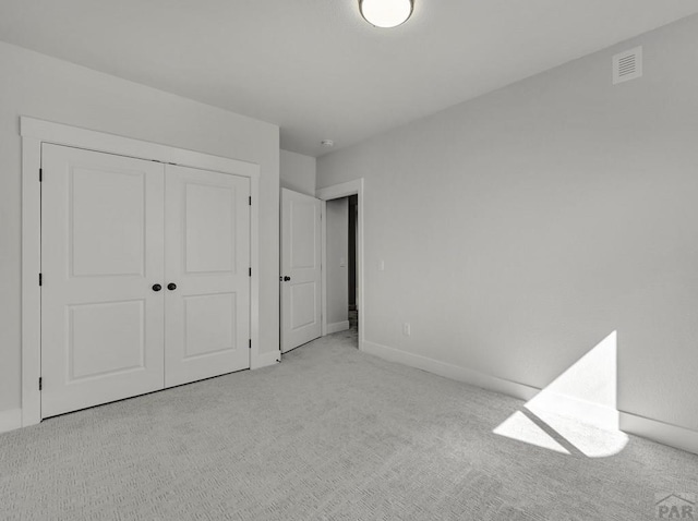 unfurnished bedroom featuring light carpet, a closet, visible vents, and baseboards