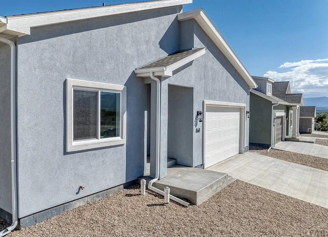 view of front of house featuring a garage, concrete driveway, and stucco siding