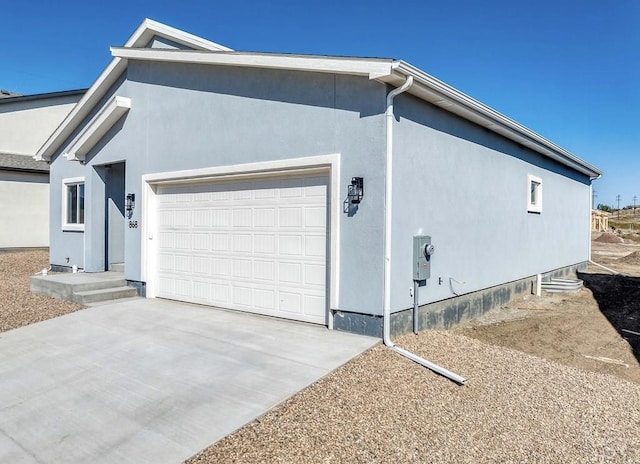 view of home's exterior with an attached garage, concrete driveway, and stucco siding