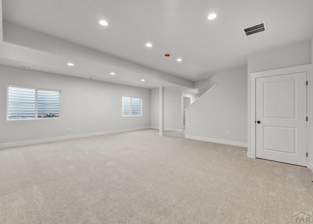 below grade area featuring light carpet, baseboards, visible vents, stairs, and recessed lighting