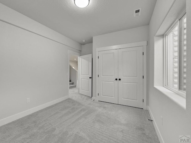 unfurnished bedroom with light carpet, multiple windows, visible vents, and baseboards