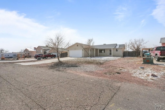 view of front of house featuring driveway, an attached garage, fence, and a residential view