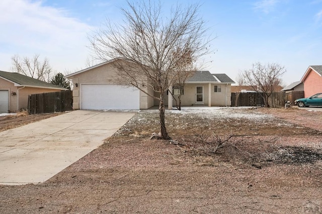 ranch-style house with driveway, an attached garage, fence, and stucco siding