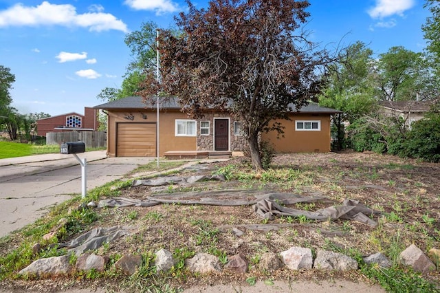 view of front of home with an attached garage, fence, concrete driveway, stone siding, and stucco siding