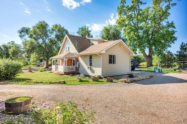 view of front facade featuring covered porch, driveway, a front lawn, and roof with shingles