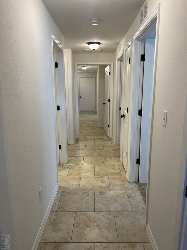 hallway with baseboards and visible vents