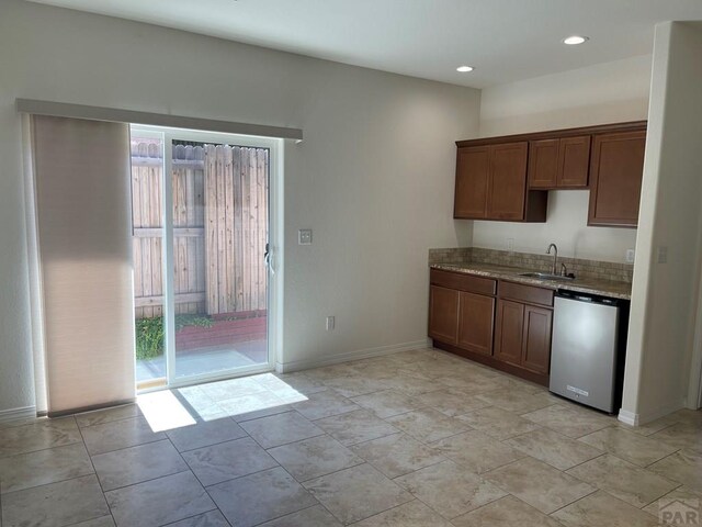 kitchen featuring baseboards, dishwashing machine, light stone counters, a sink, and recessed lighting