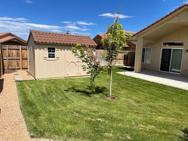 view of yard with a storage shed, a patio, an outdoor structure, and a fenced backyard