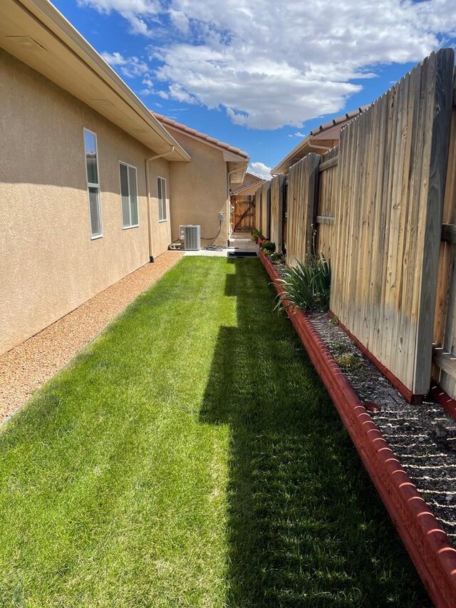 view of yard featuring central AC unit and fence