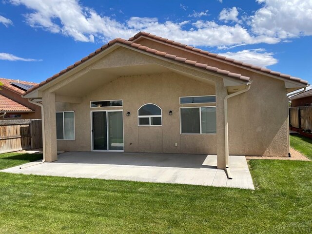 back of property with stucco siding, fence, a lawn, and a patio